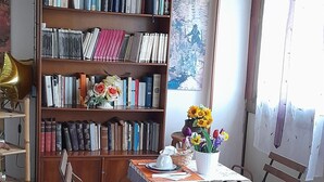 Une pièce chaleureuse avec un plafond en bois, une bibliothèque, une table à manger avec des chaises et une fenêtre avec des rideaux.