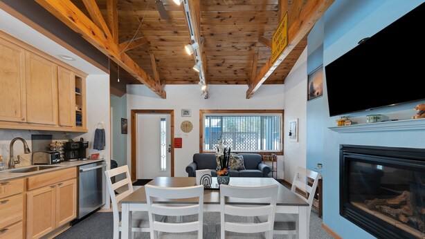 Una cocina moderna con armarios de madera, lavavajillas integrado y un comedor con sillas blancas y una mesa.