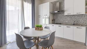 Une cuisine moderne avec des armoires blanches, un four encastré et un pare-feu décoratif.