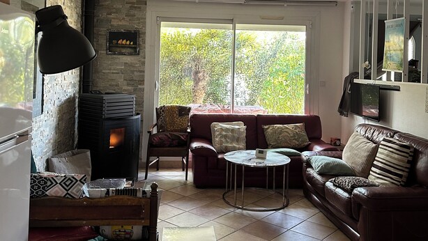 A cozy living room with a fireplace, a sofa, a coffee table, and a TV mounted on the wall.
