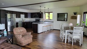 A modern kitchen with dark cabinets, stainless steel appliances, and a central island with stools.