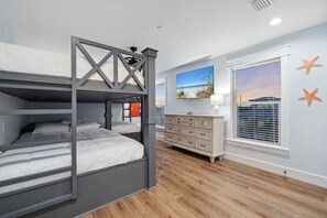 A bunk bed room with a wooden floor, a dresser, and a window with blinds. - Skyline: Rooftop Deck! Golf Cart Rental Available! (Destin)