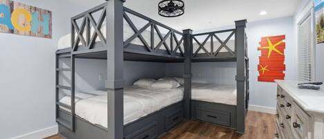 A bunk bed with a wooden frame and drawers, a ceiling fan, and a dresser with drawers.