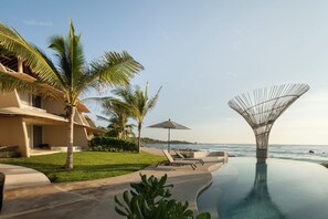 Una piscina al aire libre, sombrillas, sillones reclinables de piscina