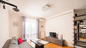 A modern living room with a grey sofa, a coffee table, a flat-screen TV, and a built-in shelf unit. - Marywilska 67 Inviting Apartment (Warszawa)