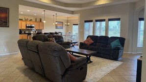 A spacious living room with a large sectional sofa, a coffee table, and a dining area in the background. - Cozy and Beautiful 30-Hac (Laguna Vista)