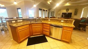 A modern kitchen with a granite countertop, wooden cabinets, and a dishwasher. - Cozy and Beautiful 30-Hac (Laguna Vista)