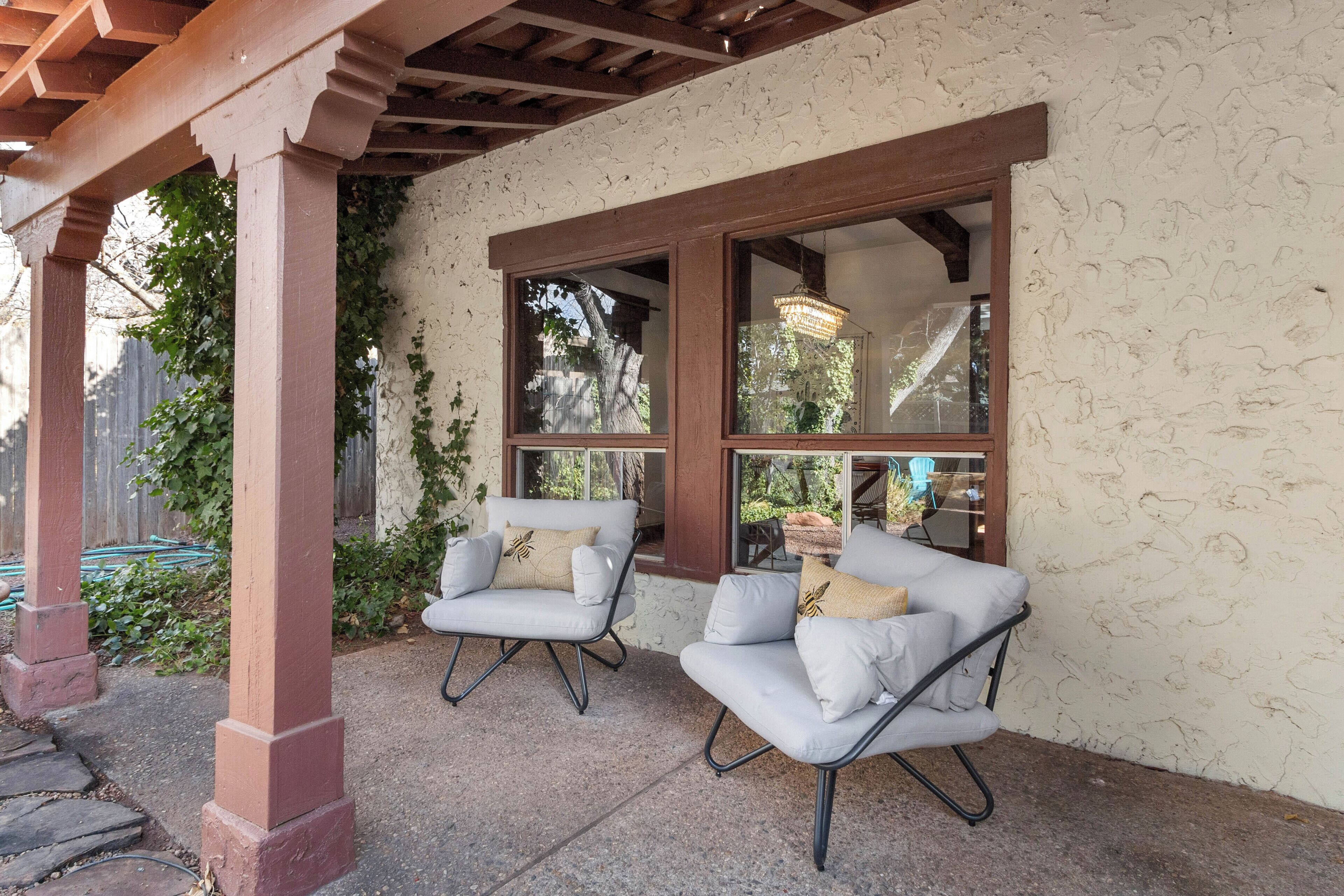 Eine überdachte Terrasse mit zwei weißen, gepolsterten Stühlen und einer Holz-Pergola.