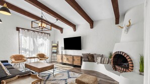 Un salon moderne doté d’une cheminée, de poutres en bois, d’un téléviseur à écran plat et d’un tapis à motifs.