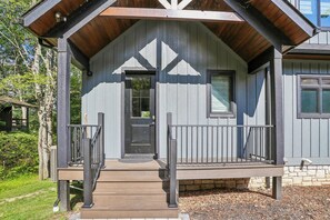 A wooden cabin with a porch, a door, and a window. - New Construction! 7 bedroom luxury lakefront  home in golf neighborhood! (Swanton)