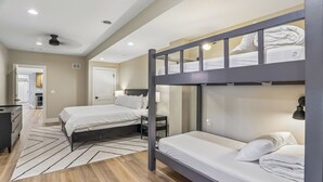 A hotel room with a bunk bed, a desk, a chair, a wardrobe, and a bathroom door. - New Construction! 7 bedroom luxury lakefront  home in golf neighborhood! (Swanton)