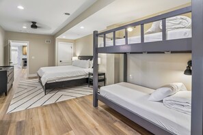 A hotel room with a bunk bed, a desk, a chair, a wardrobe, and a bathroom door. - New Construction! 7 bedroom luxury lakefront  home in golf neighborhood! (Swanton)
