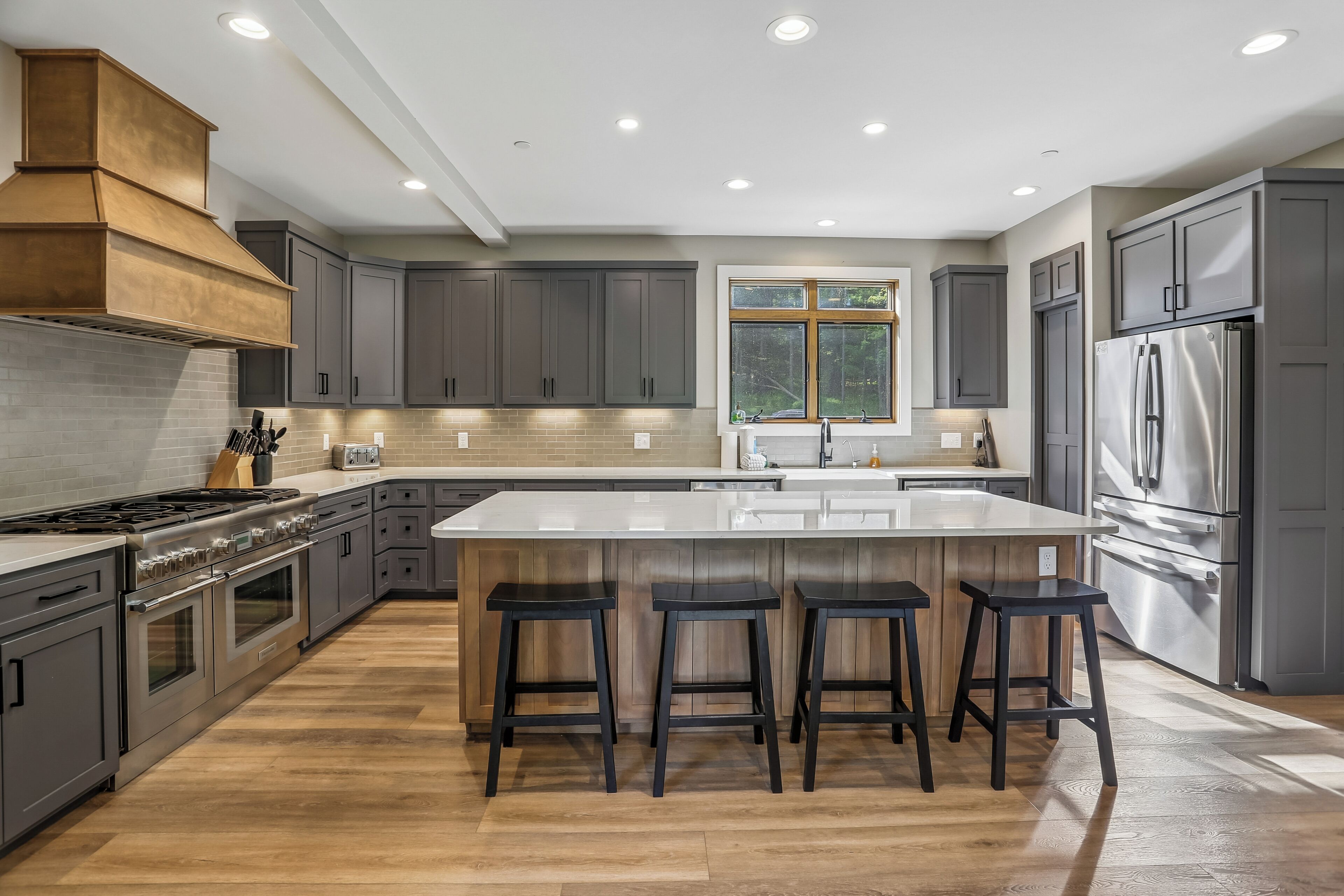 A modern kitchen with a central island, stainless steel appliances, and a large window.