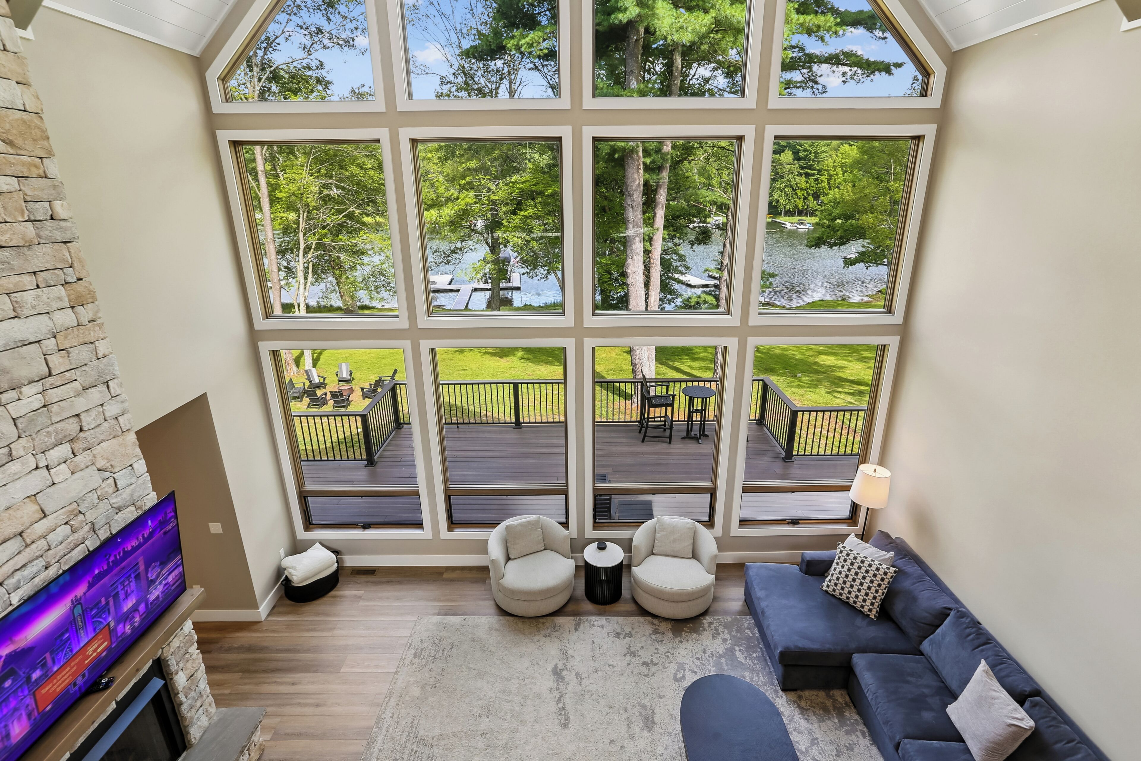 A spacious room with a large window overlooking a deck and a lake.