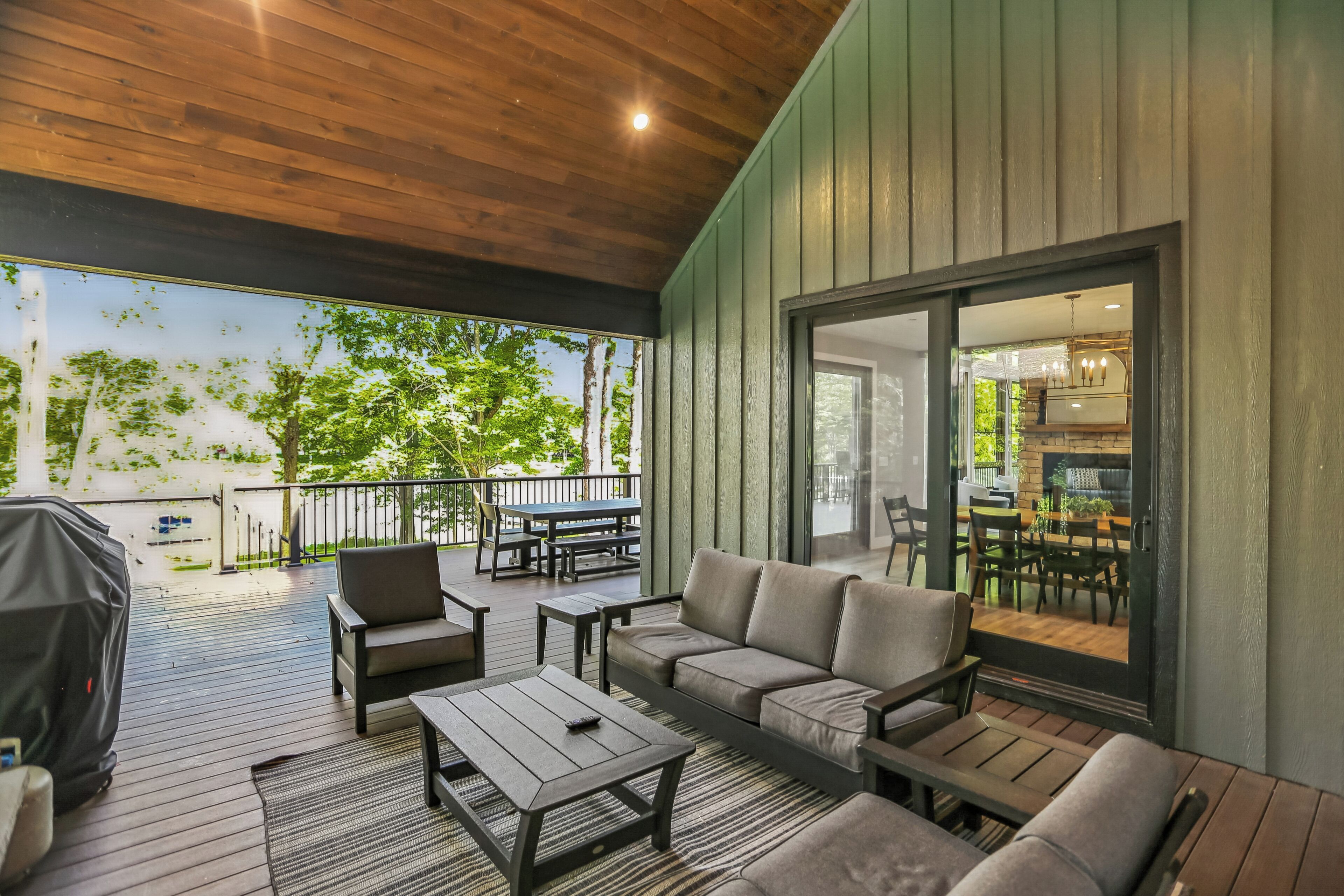 An outdoor patio with a wooden deck, seating area, and a view of the outdoors.