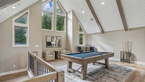 A spacious room with a pool table, a sofa, and a billiards rack. - New Construction! 7 bedroom luxury lakefront  home in golf neighborhood! (Swanton)