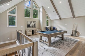 A spacious room with a pool table, a sofa, and a billiards rack. - New Construction! 7 bedroom luxury lakefront  home in golf neighborhood! (Swanton)