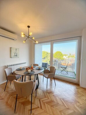 Enjoy meals in this dining area with a round table and six chairs, surrounded by a large window and a balcony view.