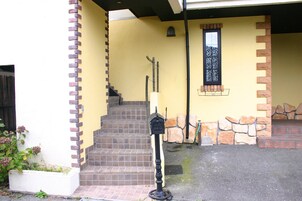 A set of outdoor stairs leading to a door, a mailbox, and a small window with a decorative grille.