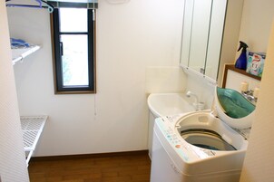 Pequeña lavandería con lavadora, lavabo y ventana.
