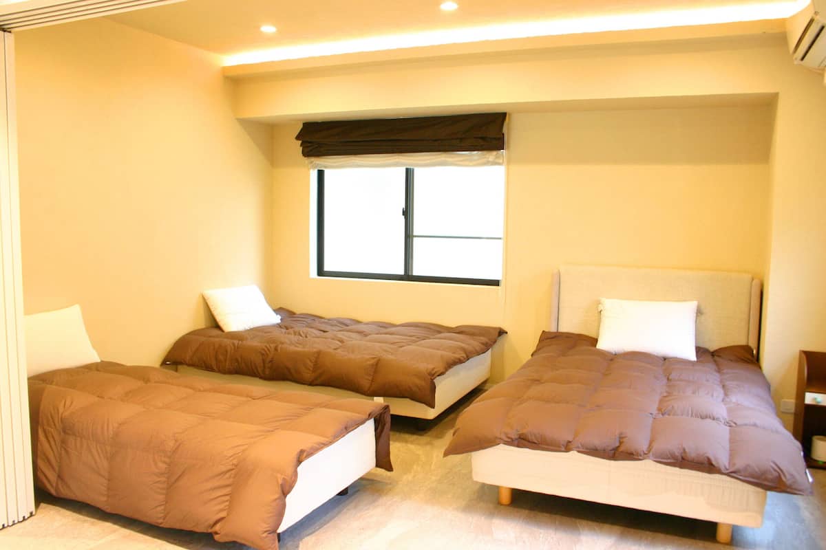 Quarto de hotel com duas camas de solteiro, uma janela com vista e uma mesa de cabeceira.
