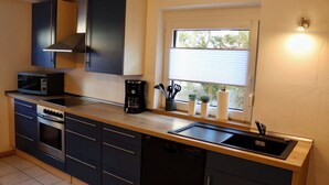 A modern kitchen with a built-in oven, microwave, and coffee maker. - Vacation apartment at Walberla (Kirchehrenbach)