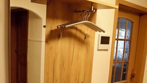 A room with a wooden wardrobe, a small shelf, and a door with frosted glass panels. - Vacation apartment at Walberla (Kirchehrenbach)