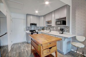 Una cocina moderna con armarios blancos, una isla de madera y un microondas sobre la encimera.