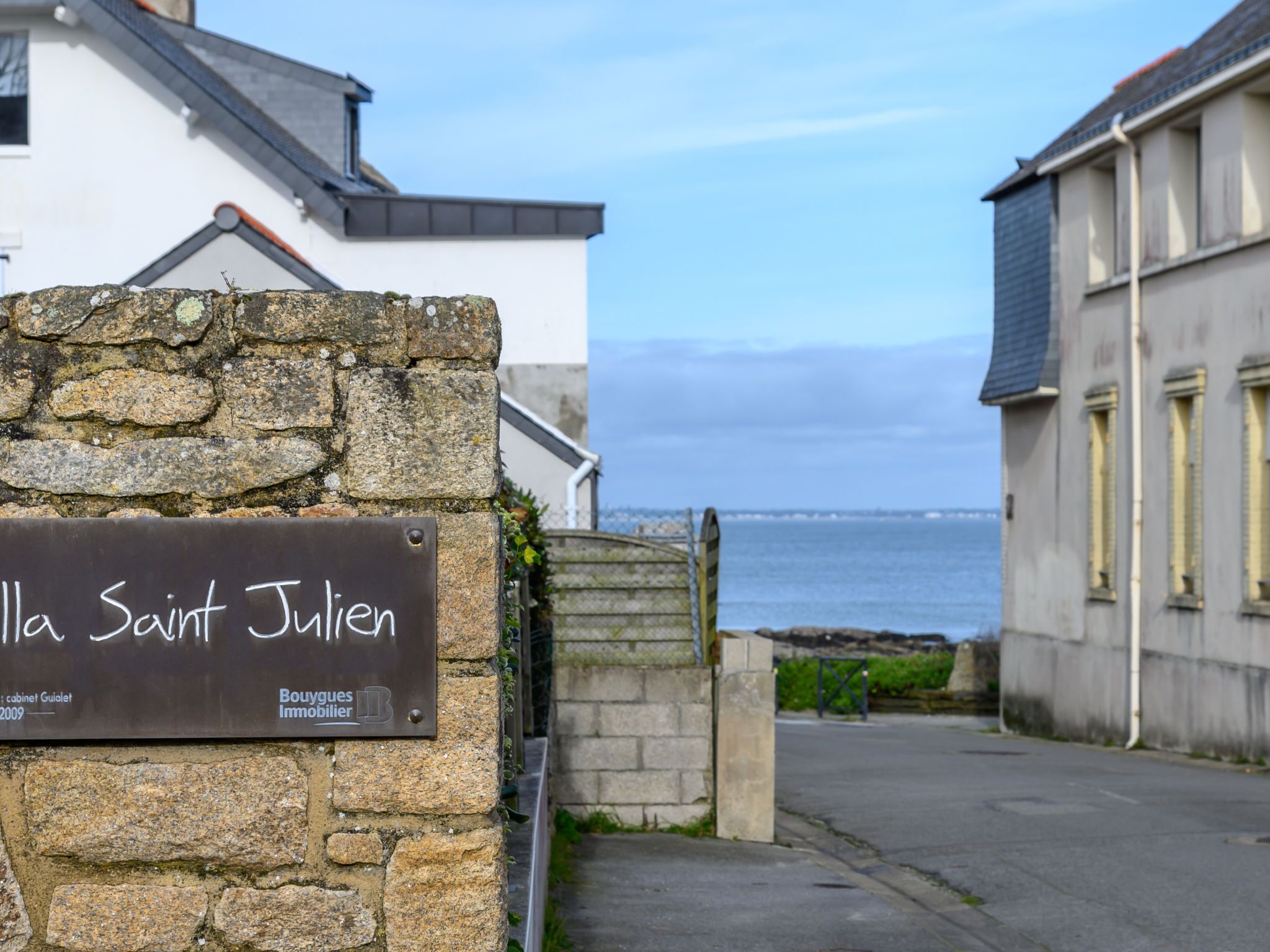 A stone wall with a sign reading "La Saint Julien" and "Boulogues Immobilier" indicating a property or hotel.