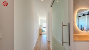 Un pasillo moderno con piso de madera, un letrero de prohibido fumar y un espejo con encimera de madera.