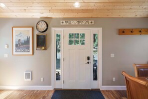 A wooden interior with a white door, a framed poster of Mt. Hood, a wall clock, and a sign indicating Bend, Oregon.