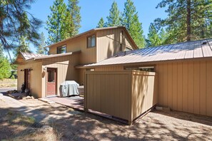 A two-story wooden cabin with a covered porch and a fenced area.