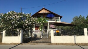 Ein zweistöckiges Haus mit Balkon, Tor und Baum mit weißen Blüten.
