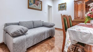 A living room with a grey sofa, a wooden cabinet, and two framed artworks on the wall.