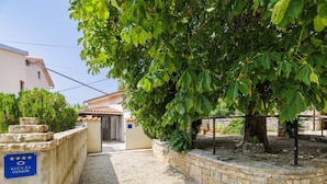 A courtyard with a stone wall, a gravel path, and a building entrance.