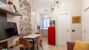Ein modernes Wohnzimmer mit Essbereich, Küche und einem roten Kühlschrank.