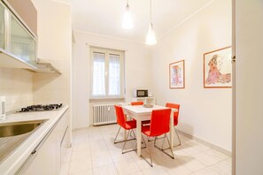 Une cuisine compacte équipée d’une cuisinière à gaz, d’un four à micro-ondes et d’un coin repas avec des chaises rouges.