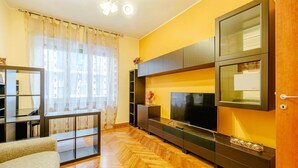 A living room with a large flat-screen TV, wooden flooring, and a modern entertainment unit. - In Turin, on Corso Rosselli, a cozy 65 sqm apartment for 4 guests, located on a raised ground floor (accessible via a few steps). Equipped with all comforts and featuring a balcony, it offers a functional and well-organized space. The area is residential (Torino)