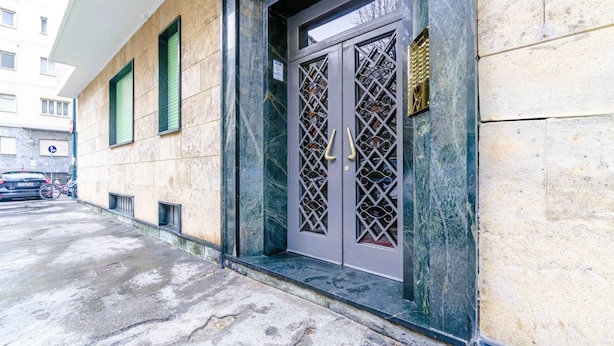 A building entrance with a metal gate, a wheelchair accessibility sign, and a small window. - In Turin, on Corso Rosselli, a cozy 65 sqm apartment for 4 guests, located on a raised ground floor (accessible via a few steps). Equipped with all comforts and featuring a balcony, it offers a functional and well-organized space. The area is residential (Torino)