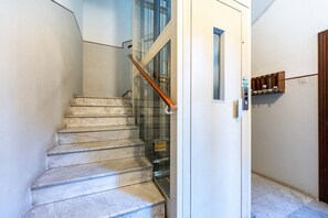 Uma escadaria com degraus de mármore que leva a uma porta de vidro.