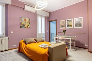 Quarto com uma cama, uma escrivaninha e uma cadeira, uma janela e uma porta.