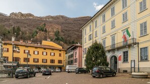 Vista da rua com carros estacionados, edifícios e uma montanha ao fundo.