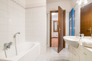 A bathroom with a bathtub, a sink, and a mirror.