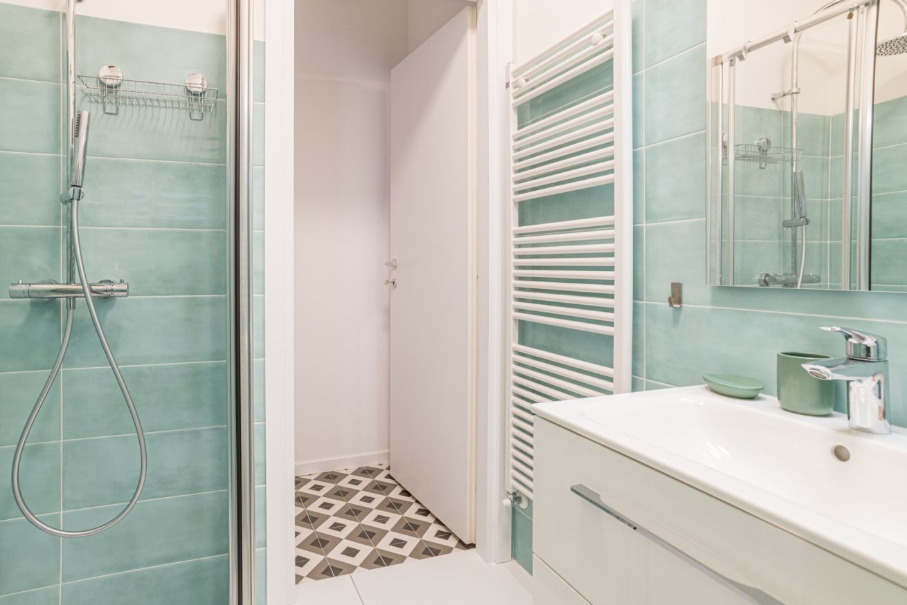 A bathroom with a shower, a sink, and a mirror.