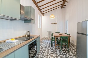 Een compacte keuken met een eethoek, met een moderne kookplaat, een spoelbak en een eettafel met stoelen.