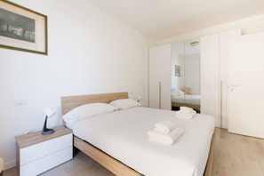 A neatly made bed with white linens and towels, a bedside lamp, and a nightstand. - GuestHost - Bright Apartment Affori, Milan (Milano)