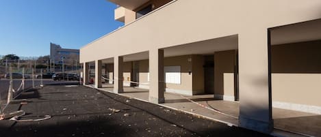 A building with multiple parking bays, a clear sky, and a distant building.
