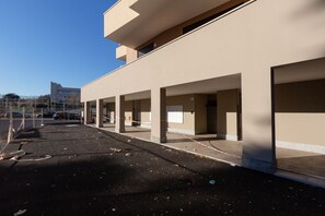 Un bâtiment doté de plusieurs places de stationnement, un ciel dégagé et un autre bâtiment visible au loin.