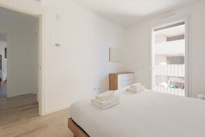 A bedroom with a bed, a nightstand, a wall-mounted light, and a door leading to a balcony. - GuestHost - Bright Apartment Affori, Milan (Milano)