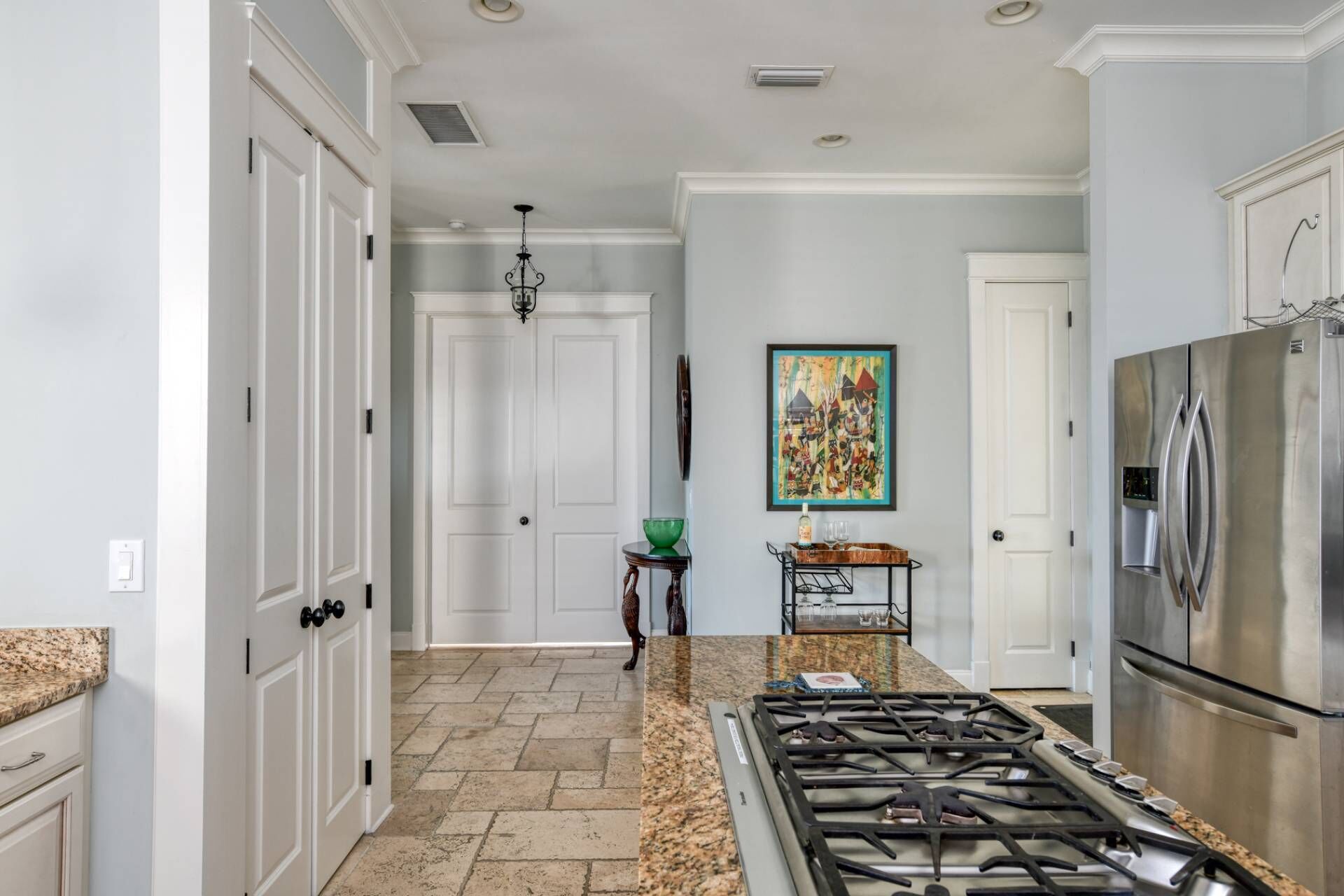 A kitchen with white cabinetry, a stainless steel refrigerator, a gas stove, and a herringbone-patterned floor.